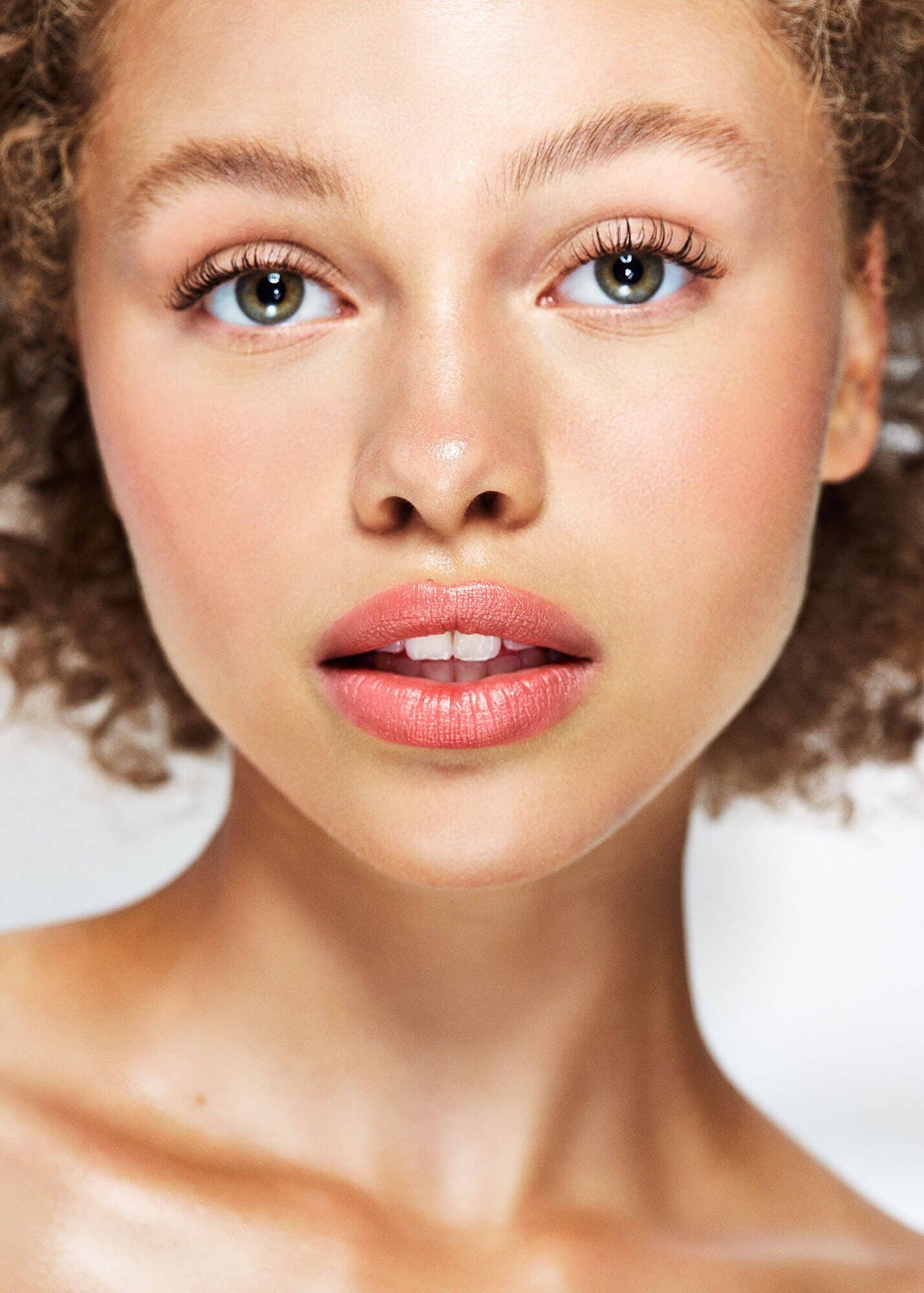 A woman with calm, glowing skin looking toward the light